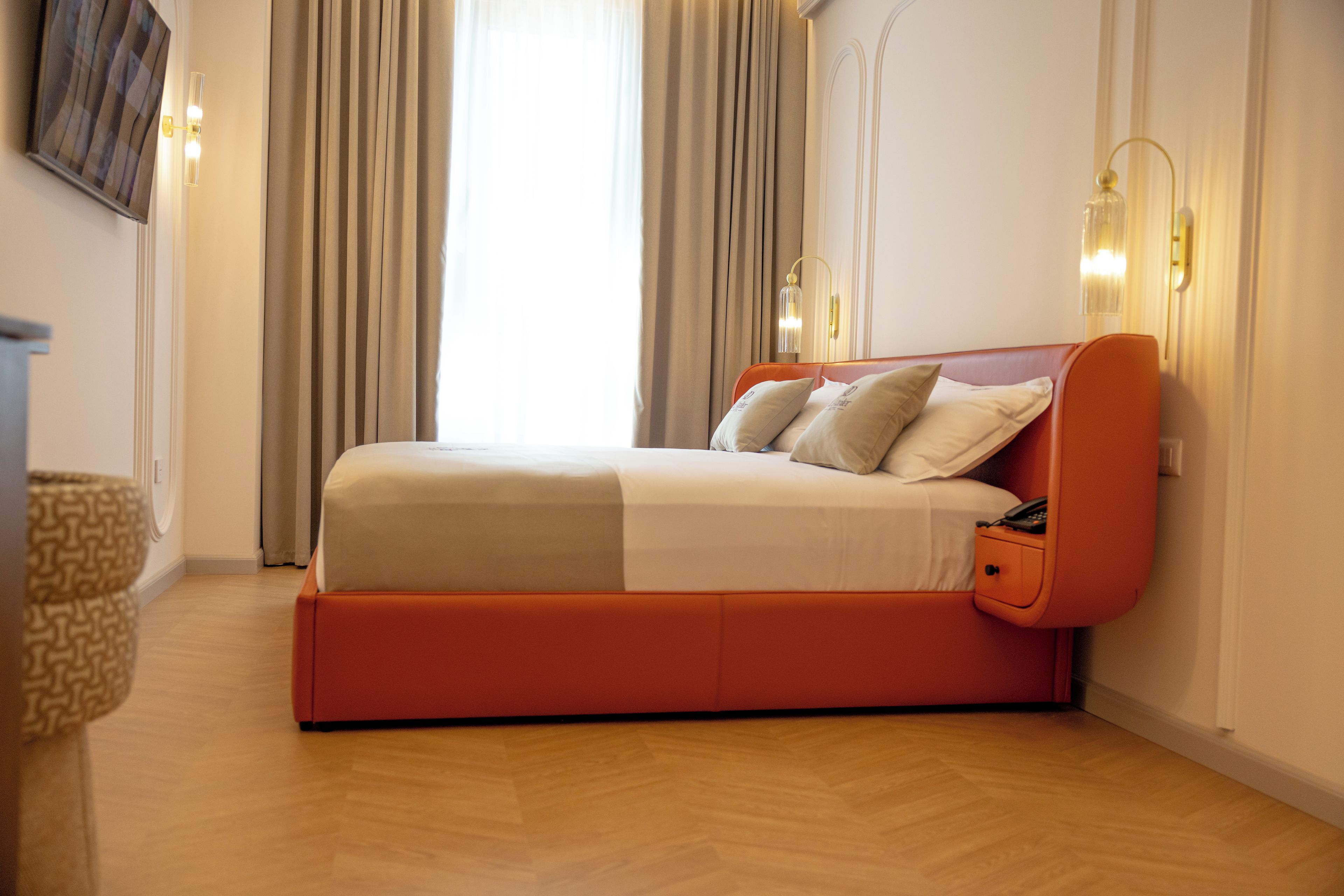 A modern bedroom with a bed, curtains, and a wall-mounted light fixture.