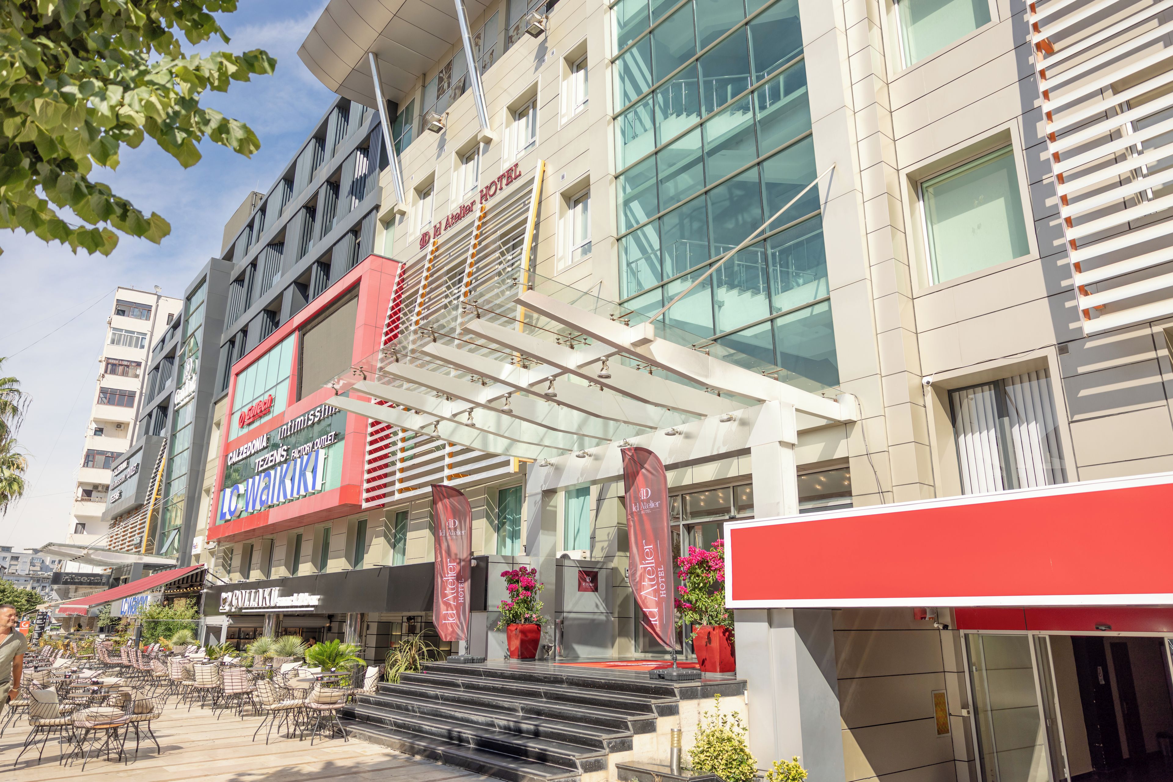 A hotel with a modern facade, multiple floors, and a ground-level outdoor seating area with tables and chairs.