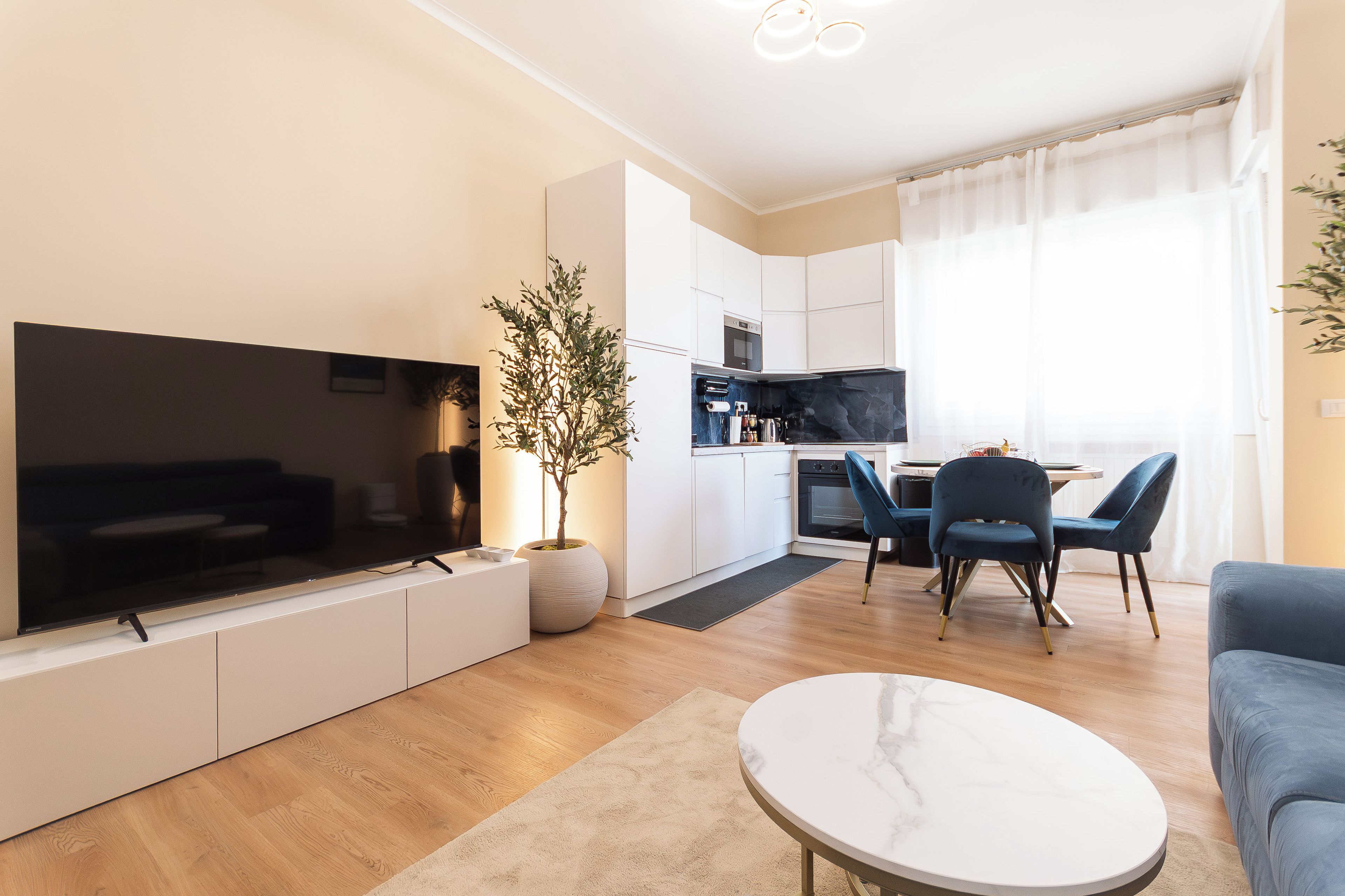 Ett modernt vardagsrum med en platt-TV, en krukväxt och en soffa.