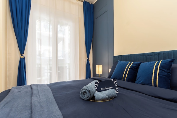 A hotel room with a bed, a pillow, a blanket, and a window with curtains.