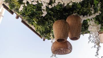 En hängkorg med vita blommor och två flätade lyktor.