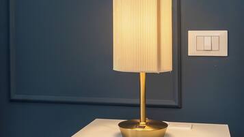 Ein Nachttisch mit Lampe, einer Schublade und einem Lichtschalter an der Wand.