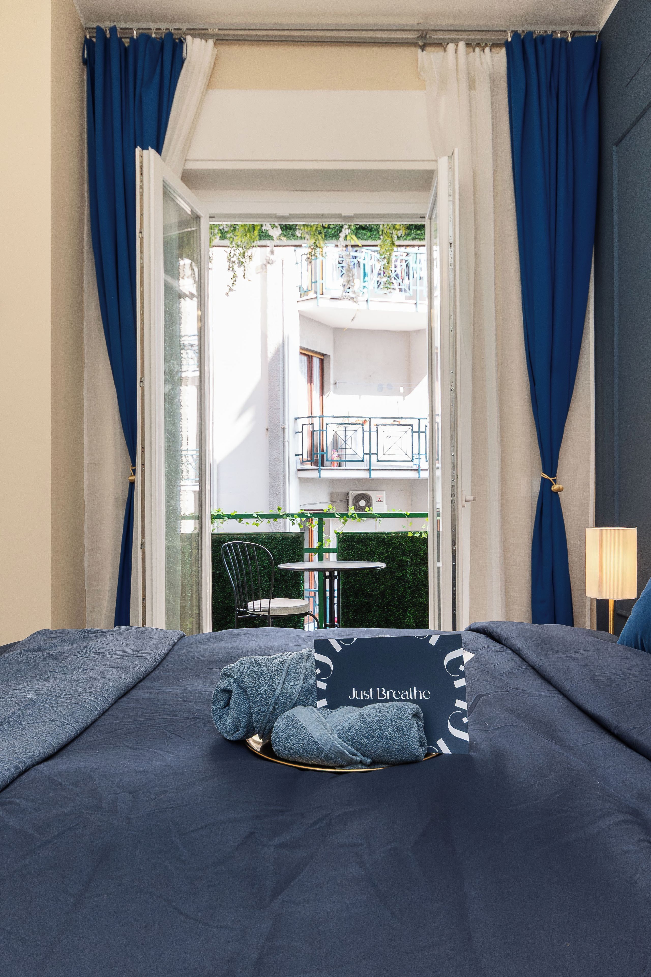 A hotel room with a bed, a view of the outdoor balcony, and a table with chairs.