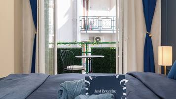 A hotel room with a bed, a view of the outdoor balcony, and a table with chairs.