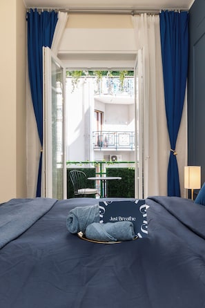 A hotel room with a bed, a view of the outdoor balcony, and a table with chairs.
