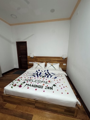 A neatly made bed with a welcome mat and a message on the bedspread. - Mandhoo Inn (Mandhoo)