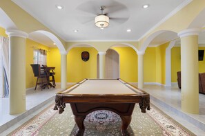 A billiards table in a room with yellow walls and white columns, a ceiling fan, and a patterned carpet. - Hospitality Expert VSV BF 3BR Chef Pool  (Montego Bay)