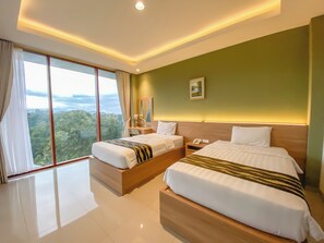 A hotel room with two beds, a desk, a phone, and a view of the outdoors. - RUKUN Place Bandung  (Kota Bandung)