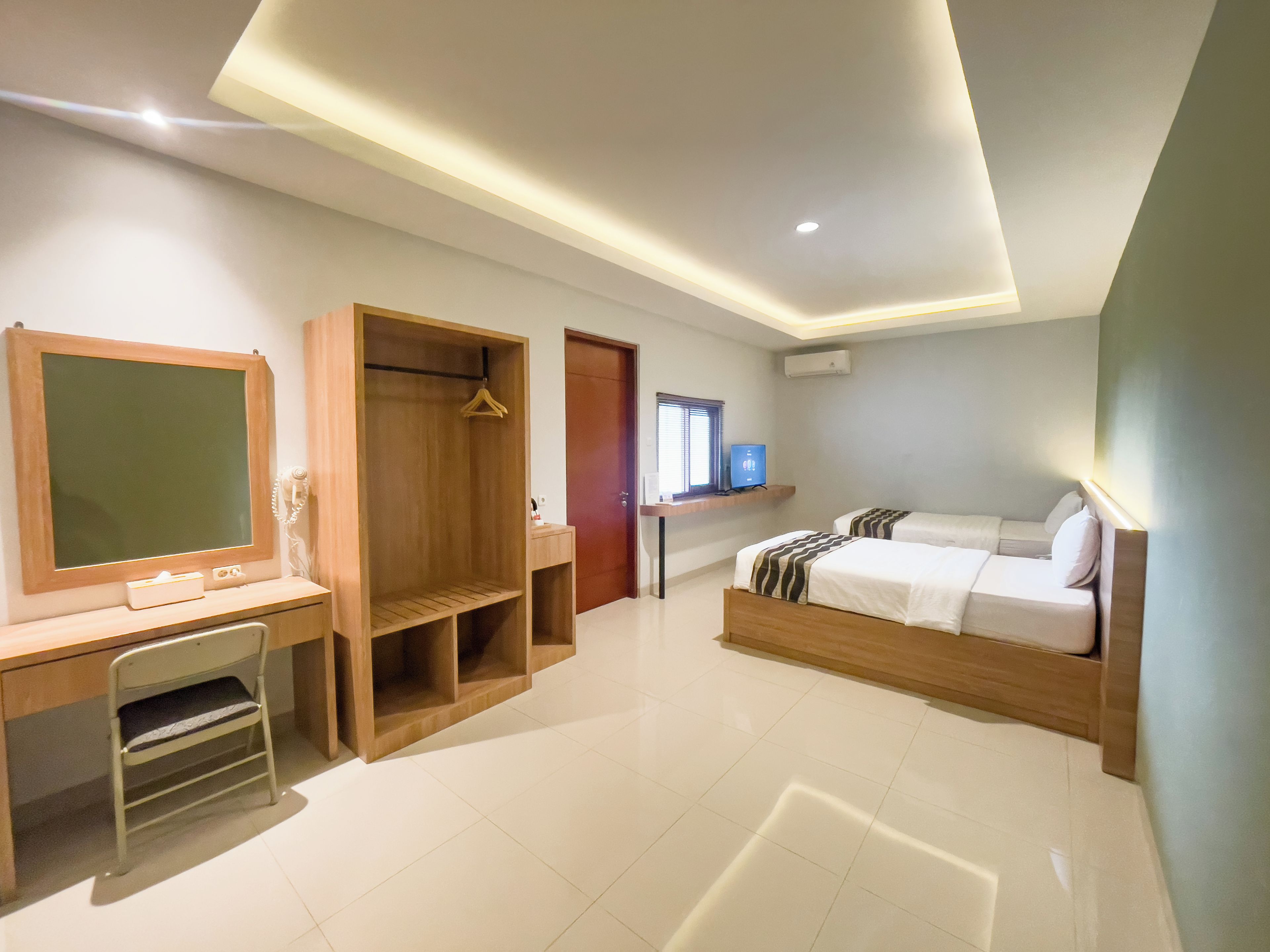 A hotel room with a desk, a bed, a wardrobe, and a television.