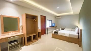 A hotel room with a desk, a bed, a wardrobe, and a television.
