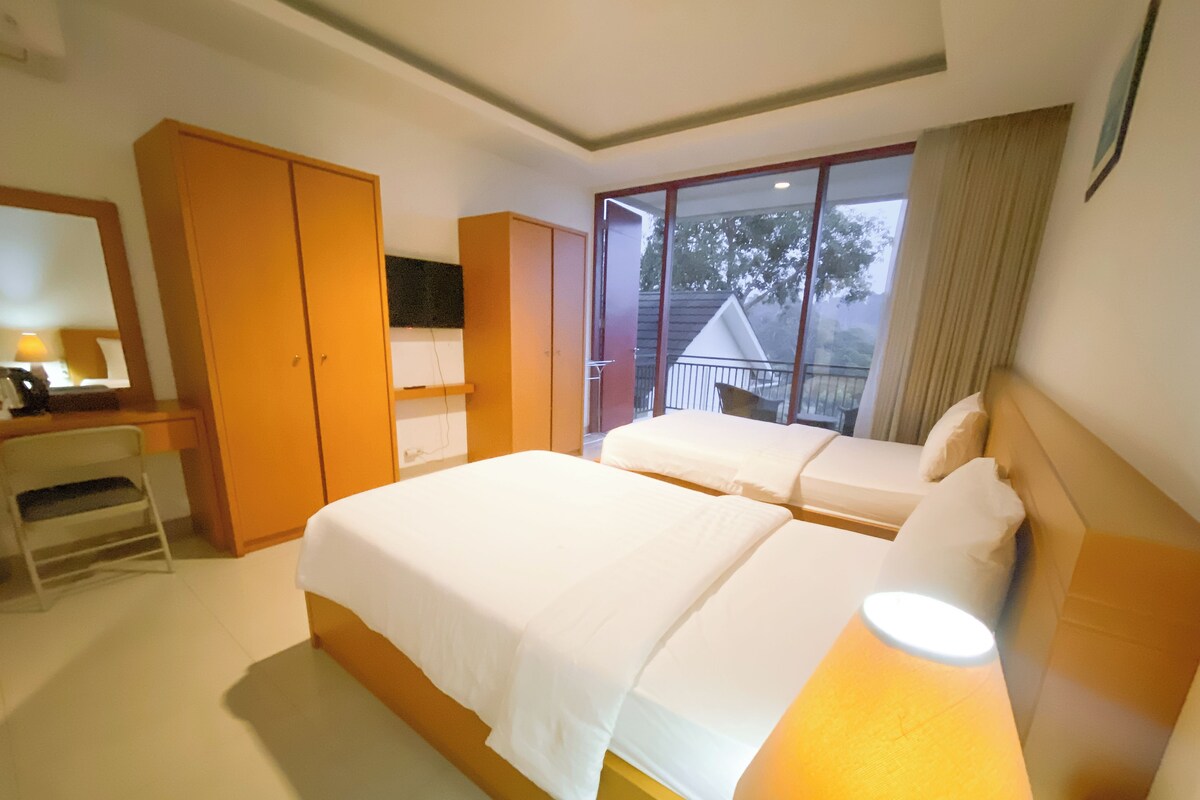 A hotel room with a large bed, a desk, a wardrobe, and a balcony with a view.