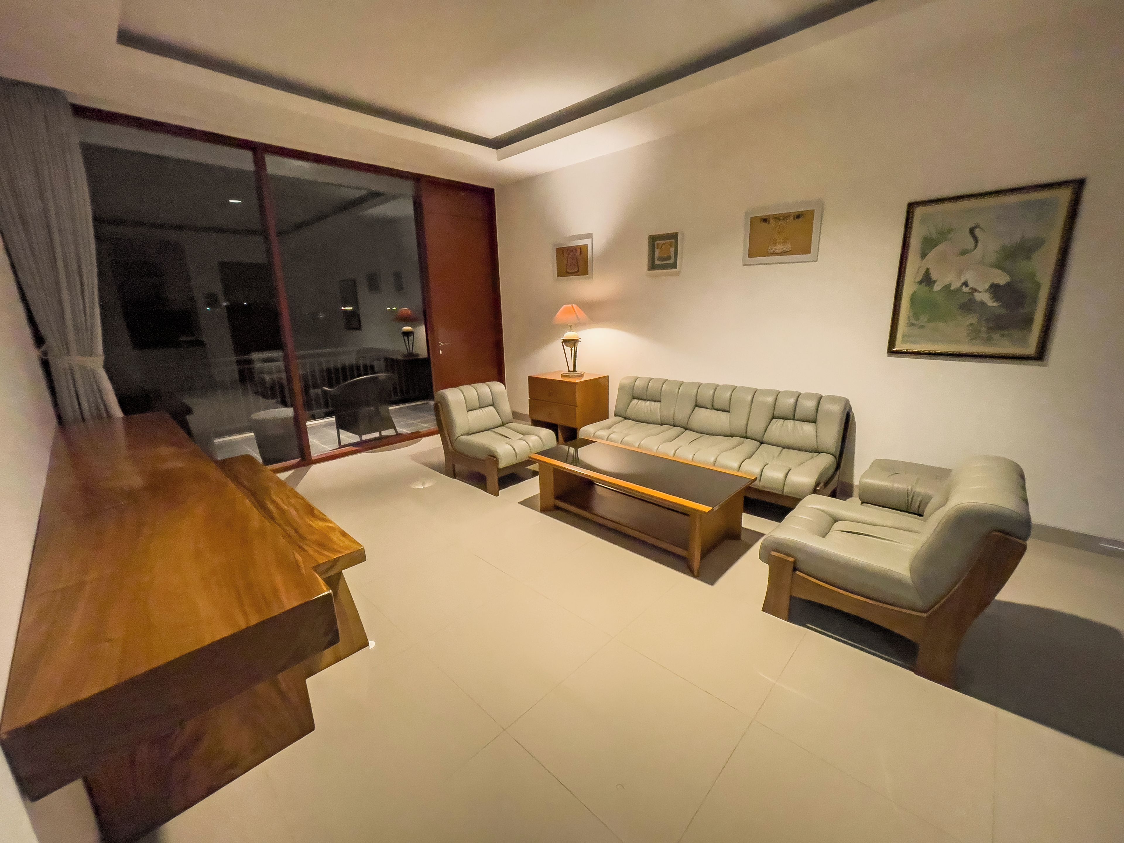A modern living room with a sofa, two armchairs, a coffee table, and a wooden side table.