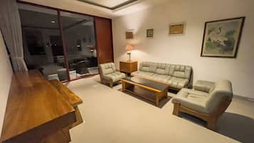 A modern living room with a sofa, two armchairs, a coffee table, and a wooden side table.