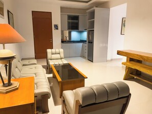 A modern living room with a sofa, a coffee table, and a wooden bench. - RUKUN Place Bandung  (Kota Bandung)