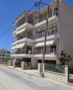 Un edificio residencial de varios pisos con balcones, un camino de entrada cerrado y cielo despejado.