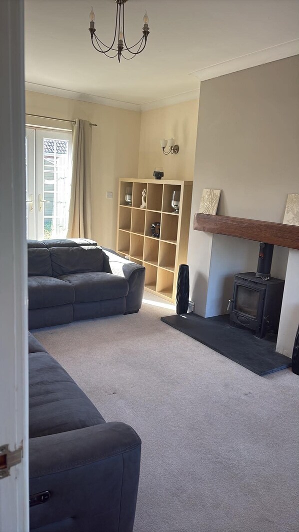 A living room with a sectional sofa, a fireplace, a built-in shelving unit, and a chandelier.