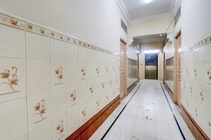 Un couloir aux carreaux décoratifs, avec une porte au fond.