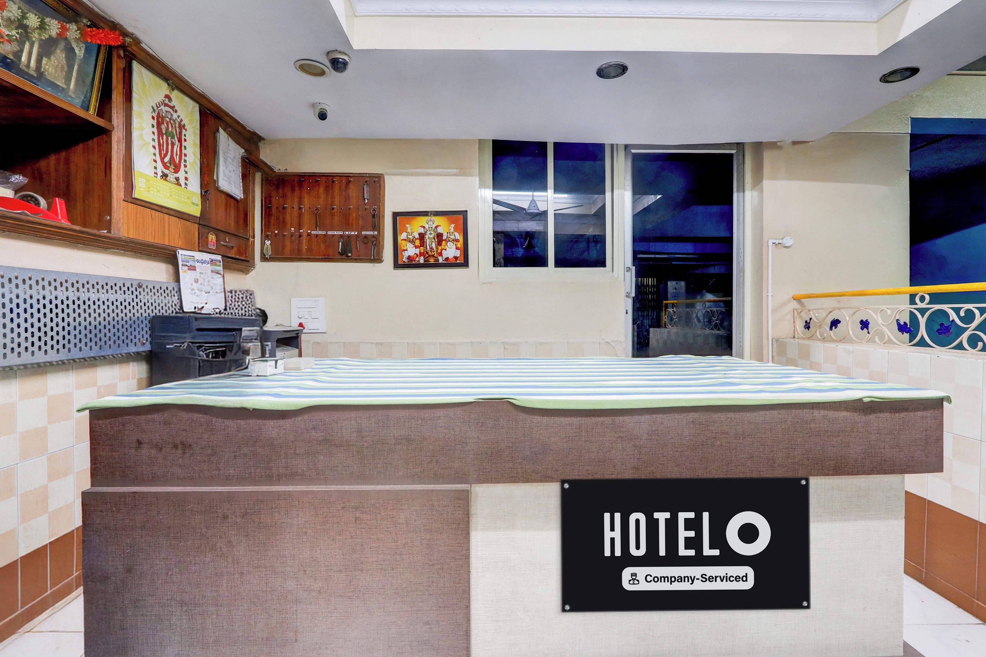 Habitación de hotel con cama, señal que indica hotel de servicio para empresas, cámara de seguridad en la pared y ventana con vista al cielo nocturno.