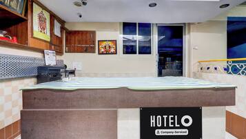 Habitación de hotel con cama, señal que indica hotel de servicio para empresas, cámara de seguridad en la pared y ventana con vista al cielo nocturno.