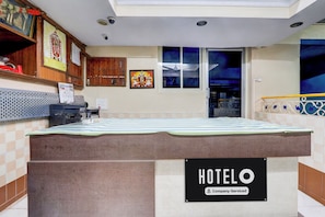 Habitación de hotel con cama, señal que indica hotel de servicio para empresas, cámara de seguridad en la pared y ventana con vista al cielo nocturno.
