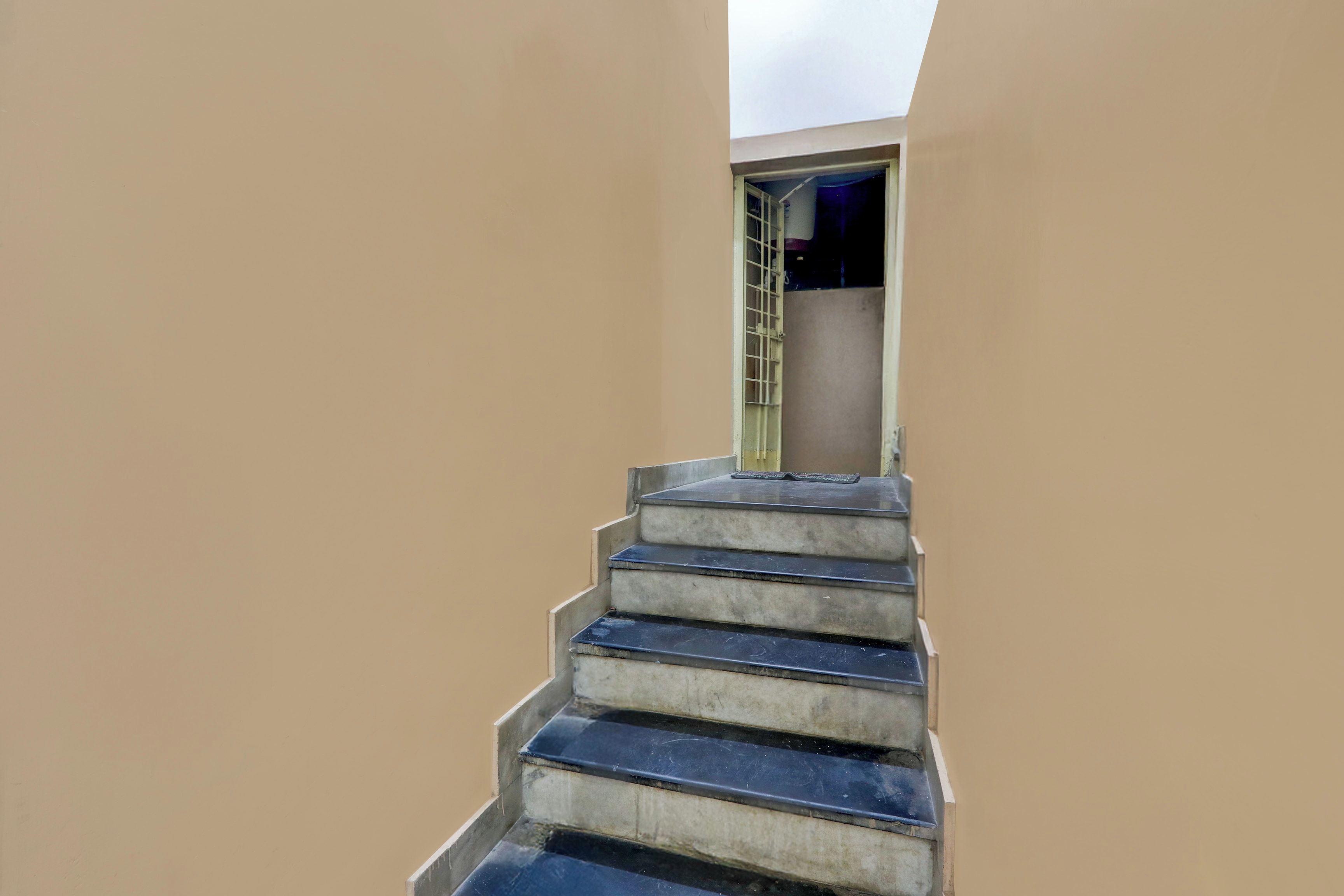 A concrete staircase leading to a door with a metal grille.