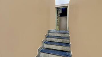 A concrete staircase leading to a door with a metal grille.
