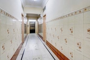 Un pasillo con paredes y piso de baldosas, que conduce a una puerta al final.