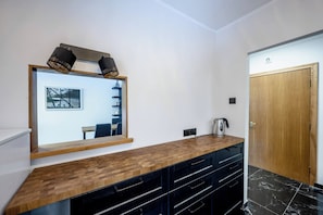 Un bagno moderno con un mobile bagno in legno, cassetti neri, uno specchio con cornice e una porta in legno.