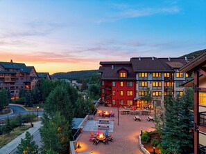 A hotel courtyard with outdoor seating, a fire pit, and a view of the surrounding buildings and landscape. - Steps To Winter Park Gondola • Shared Hot Tub + Pool | Little Moose (Winter Park)