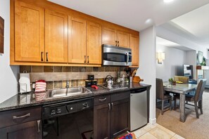 Une cuisine moderne avec des meubles en bois, des appareils électroménagers en acier inoxydable et un coin repas comprenant une table et des chaises.