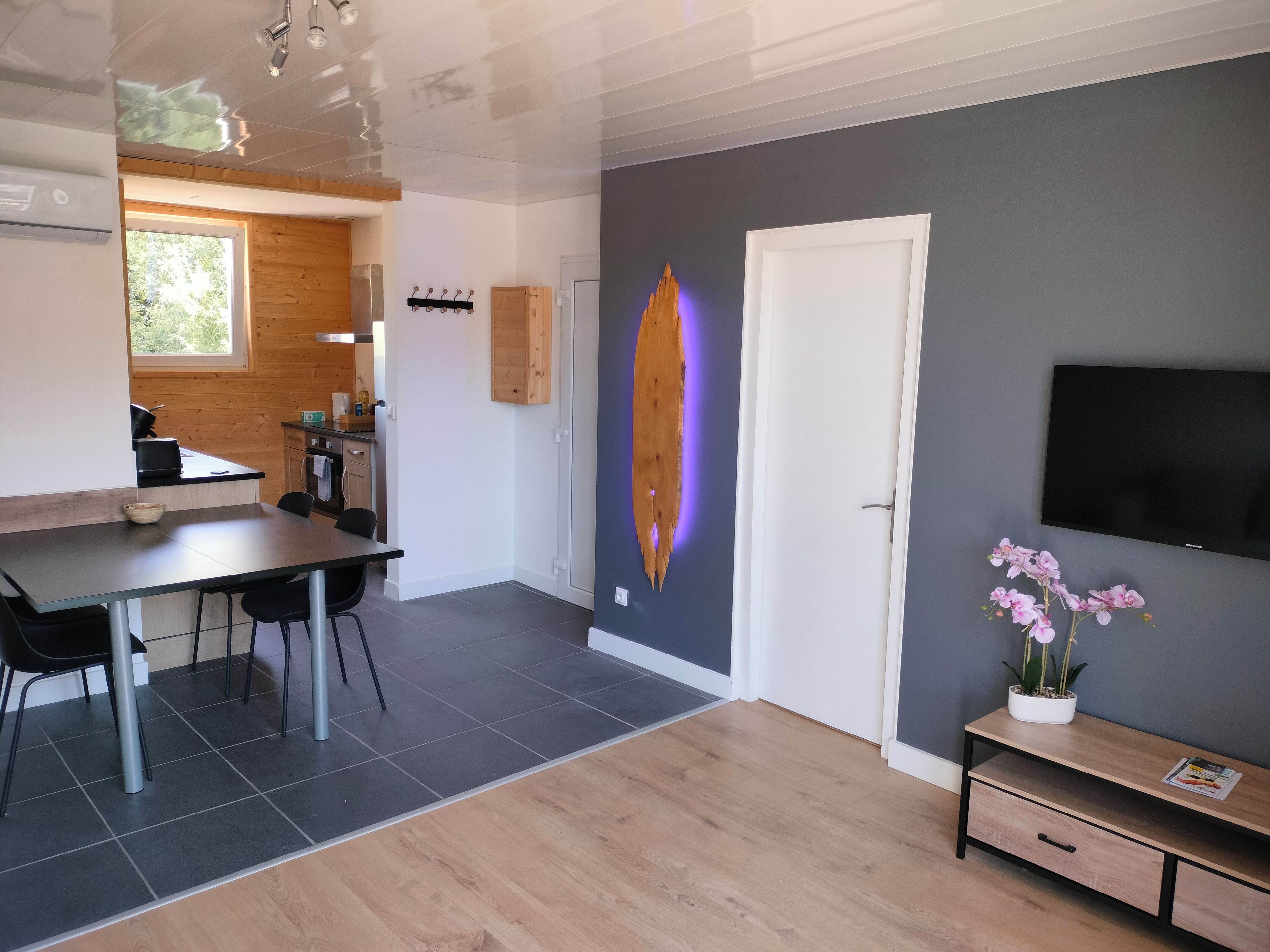 Een moderne keuken met een eethoek, een flatscreen televisie en een houten kast.