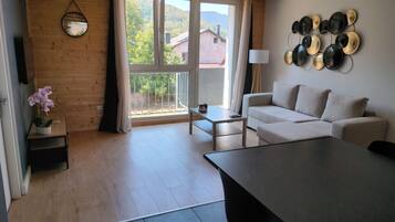 Ein modernes Wohnzimmer mit einer Couch, einem Esstisch und Blick auf einen Balkon.
