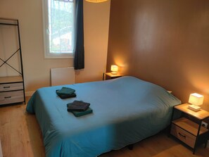 Ein Schlafzimmer mit einem Bett, zwei Nachttischen, einem Fenster mit Vorhängen und einer Heizung.