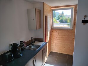 Cuina compacta amb finestra, armari encastrat i taulell amb cafetera i torradora.