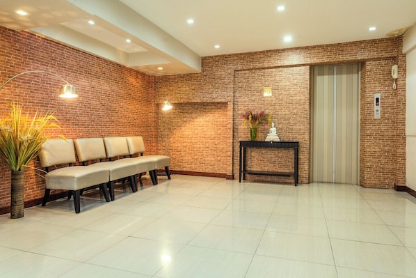 A waiting area with a bench, a vase with flowers, and an elevator. - SHRI VRINDAVAN (Bangkok)