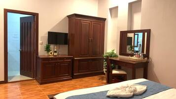 A hotel room with a bed, a desk, a wardrobe, and a mirror.