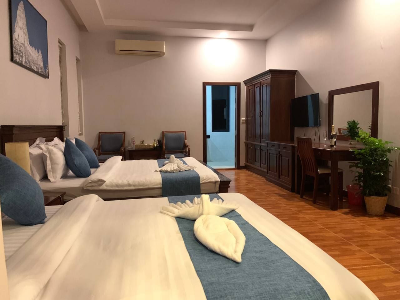 A hotel room with two beds, a desk, a chair, a television, and a mirror.