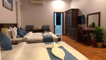 A hotel room with two beds, a desk, a chair, a television, and a mirror.