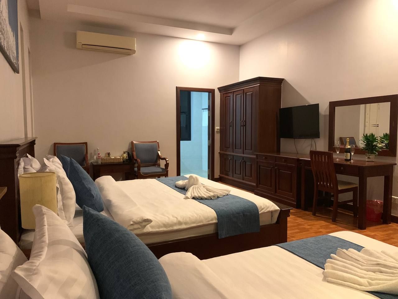 A hotel room with two beds, a desk, a chair, a television, and a wardrobe.