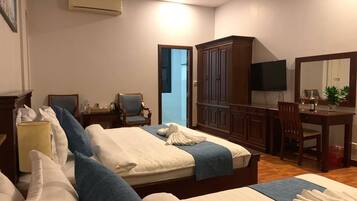 A hotel room with two beds, a desk, a chair, a television, and a wardrobe.