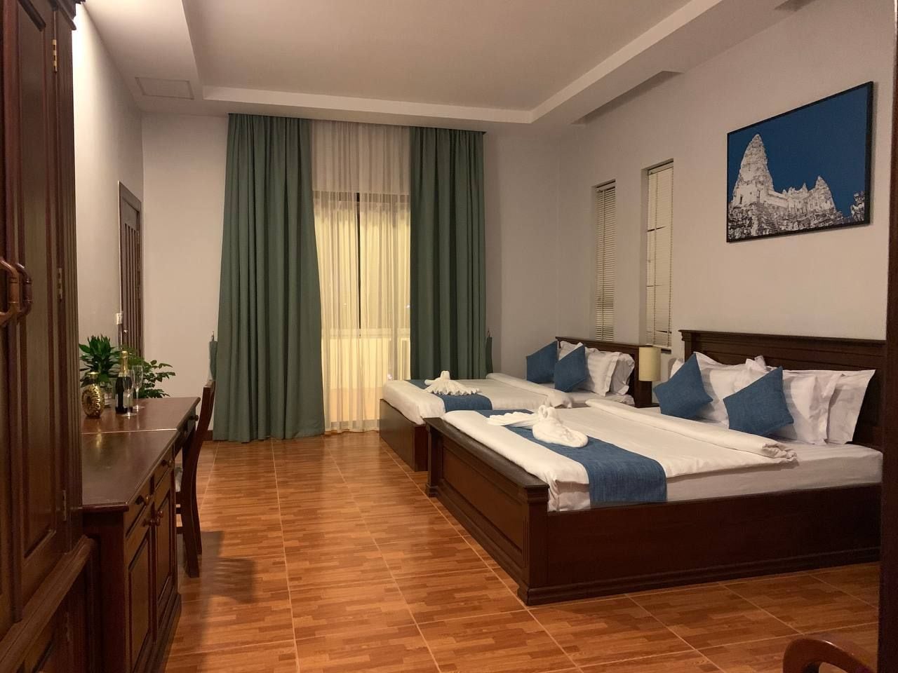 Une chambre d’hôtel avec un lit en bois, un bureau et un coin repas.
