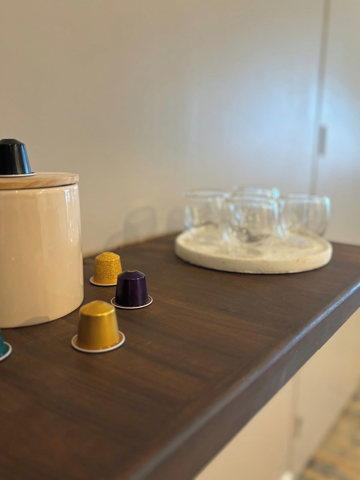 Een houten tafel met een keramieken pot en een dienblad met glazen.