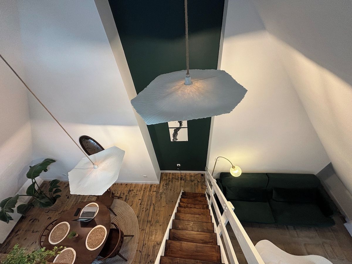 A modern interior with a staircase, a dining area, and a hanging light fixture.