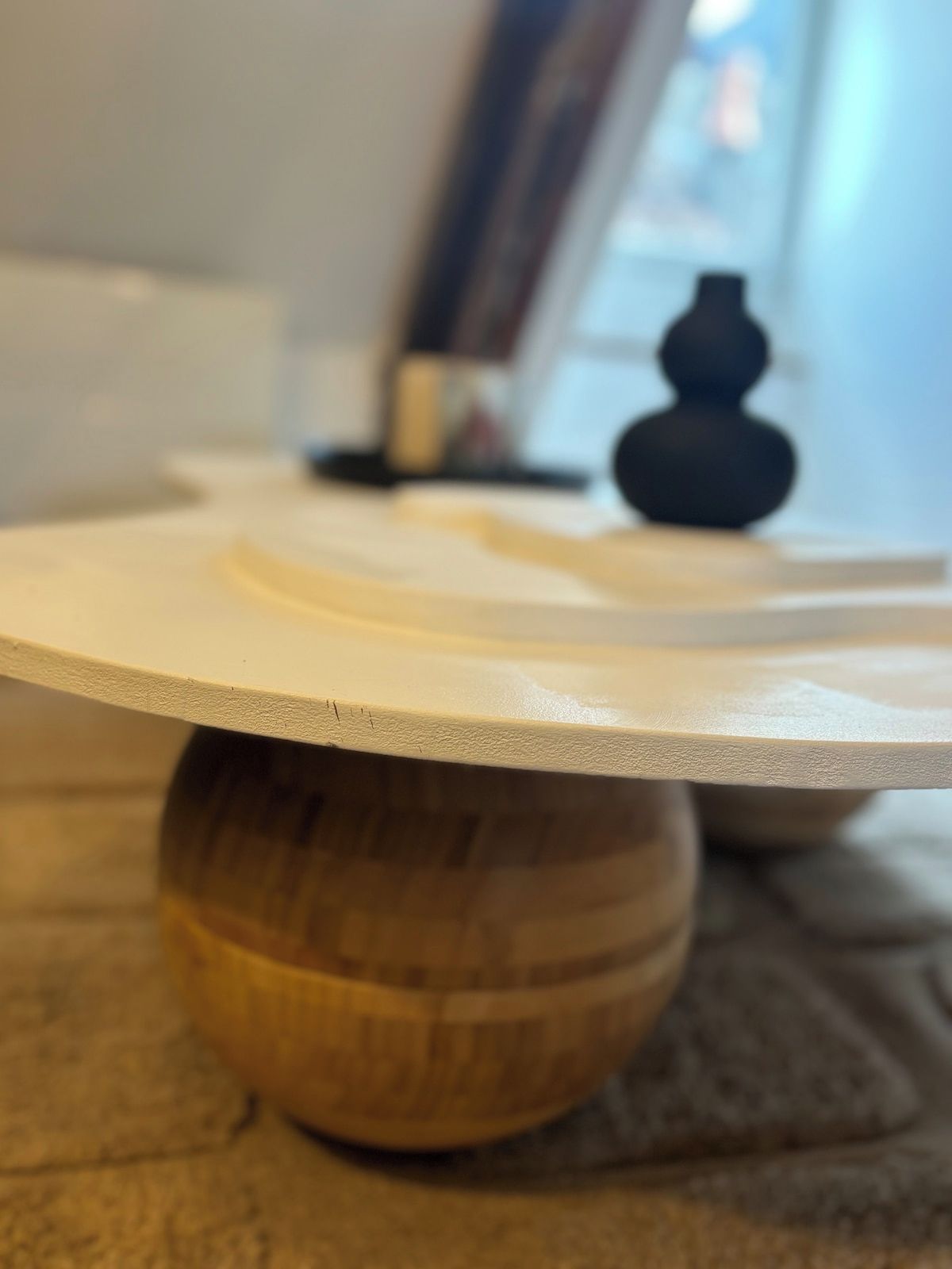 Een houten tafel met een rond, plat blad en een ronde voet.