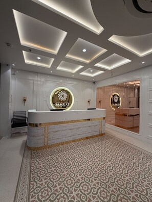 A hotel reception area with a marble counter, patterned floor, and recessed ceiling lighting. - Hotel Samrat Sheraton (Varanasi)