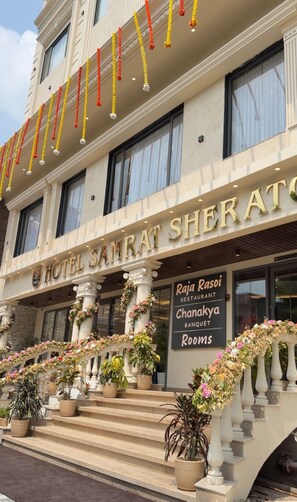 A hotel entrance with a sign for 'Hotel Samrat Sheraton' and 'Raja Rasoï Restaurant Chanakya Banquet Rooms'. - Hotel Samrat Sheraton (Varanasi)