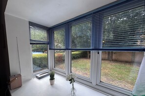 A room with large windows, a potted plant, and a small table. - Bright 2BDR Apt with Garden View in Greenwich (London)