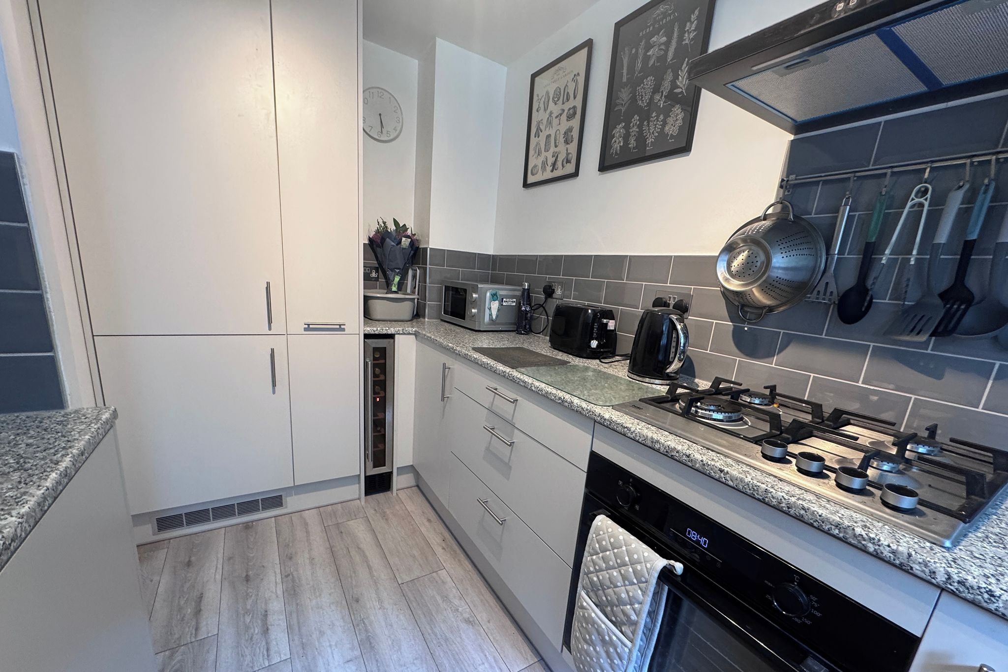 A modern kitchen with white cabinets, a granite countertop, a stove, a microwave, and a dishwasher.