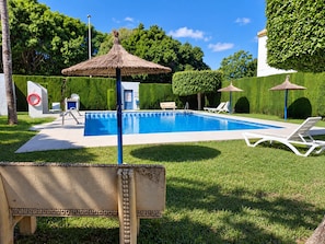 A swimming pool with lounge chairs and a thatched umbrella. - Jardin del Mar House Torrevieja (Torrevieja)