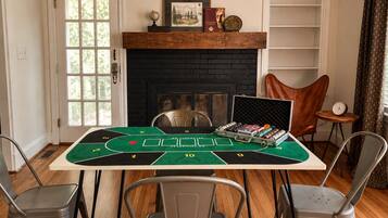 A room with a poker table set up for a game, a fireplace, and a bookshelf.